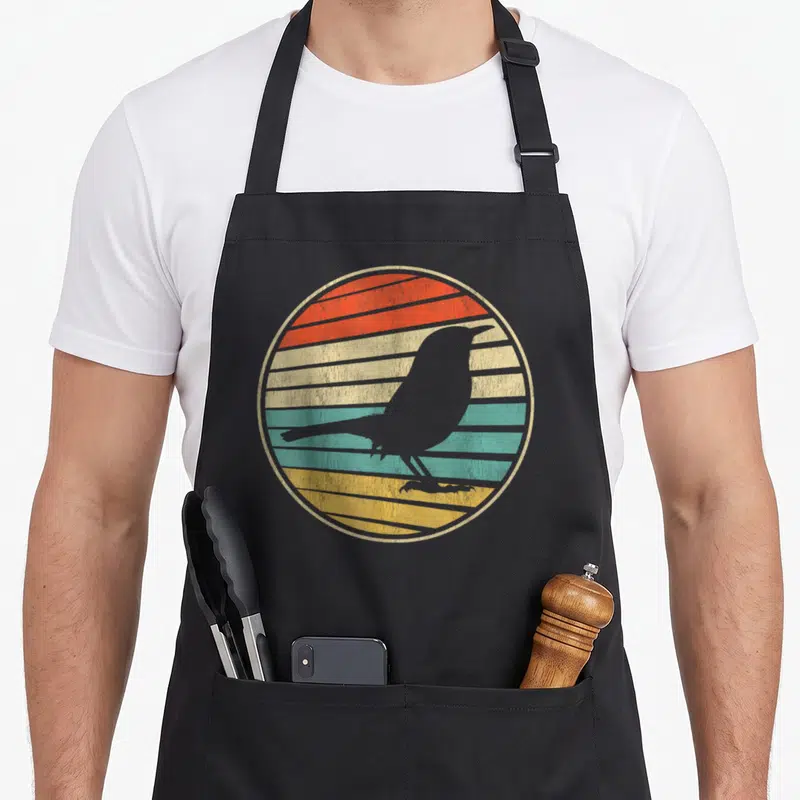 Tablier de cuisine noir avec silhouette d'oiseau sur fond circulaire rayé orange jaune et turquoise