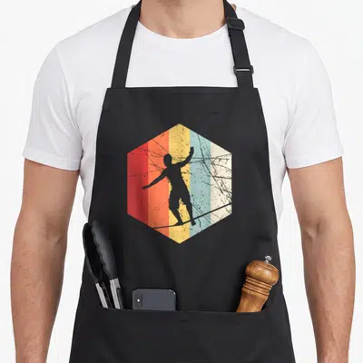 Tablier de cuisine noir avec silhouette de slackliner sur corde dans un hexagone aux bandes colorées et texture vieillie