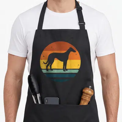 Tablier de cuisine noir avec silhouette de chien Whippet sur fond de soleil couchant coloré style rétro.
