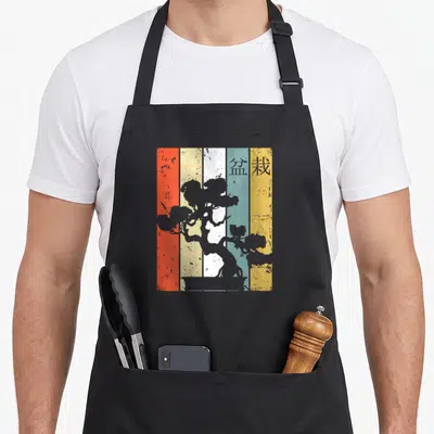 Tablier de cuisine noir avec illustration retro d'un arbre bonsai sur fond de bandes verticales colorées et texturées.