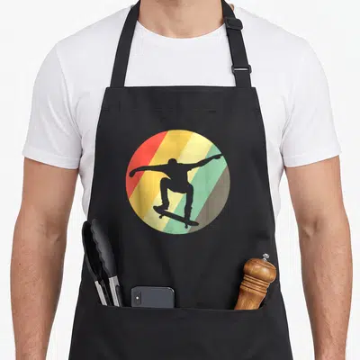 Tablier de cuisine noir avec un skieur en silhouette sur un cercle aux bandes diagonales colorées.