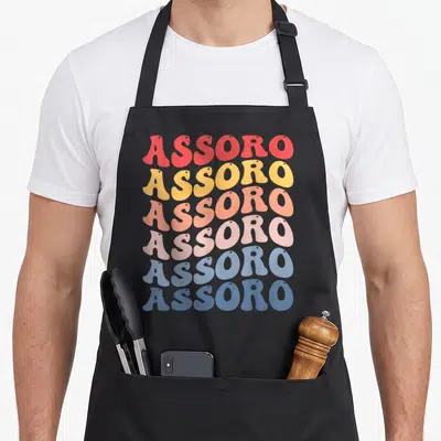 Tablier de cuisine noir avec le texte Assoro répété en lettres ondulées multicolores style rétro.