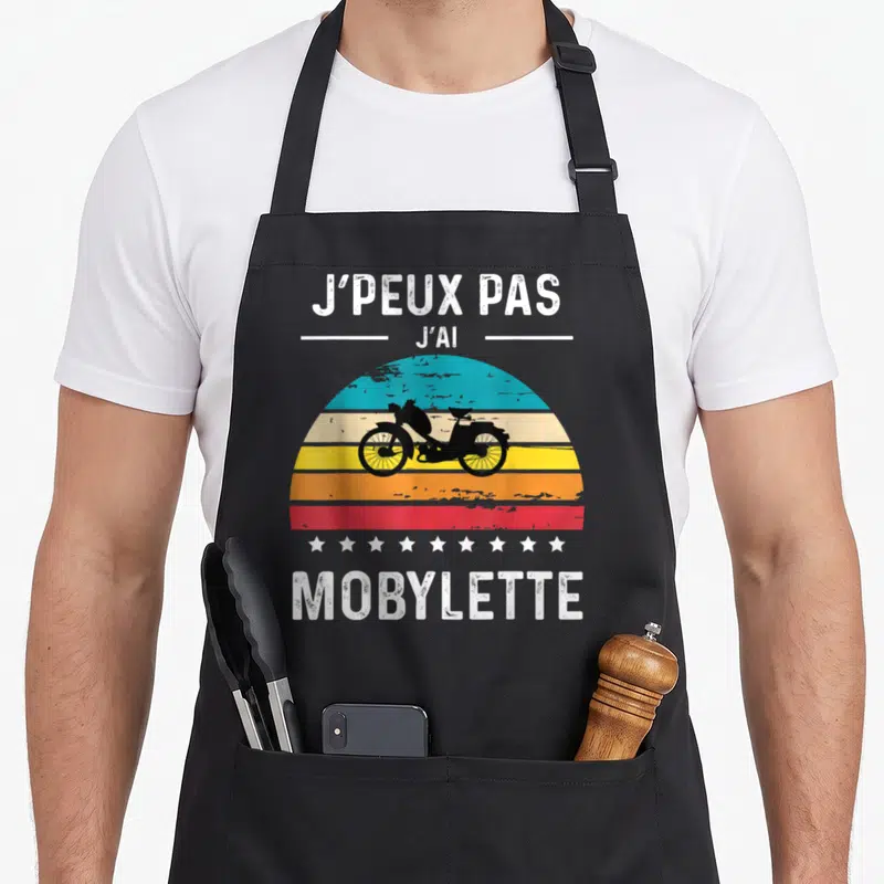 Tablier de cuisine noir avec illustration Mobylette rétro et texte J'peux pas j'ai sur fond de soleil couchant coloré.