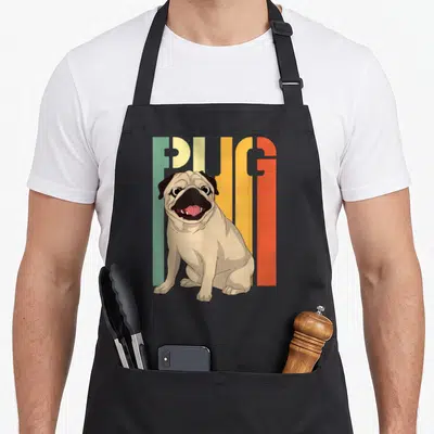 Tablier de cuisine noir avec illustration d'un pug carlin et le mot PUG en lettres vertes jaunes et oranges.