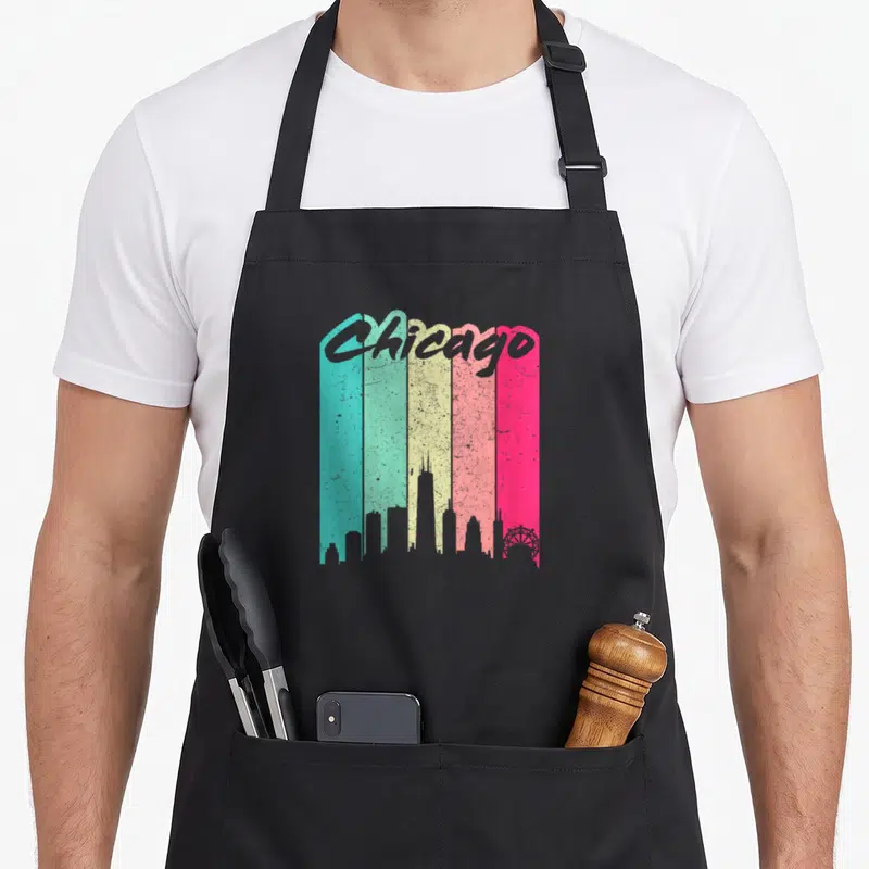 Tablier de cuisine noir avec skyline rétro de Chicago sur fond de bandes verticales colorées turquoise, jaune et rose vif.