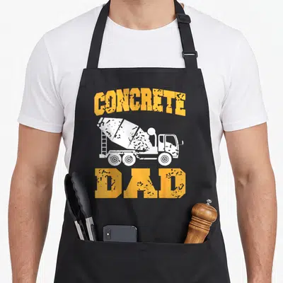 Tablier de cuisine noir avec illustration d'un camion-benne blanc et texte orangeConcrete Dad