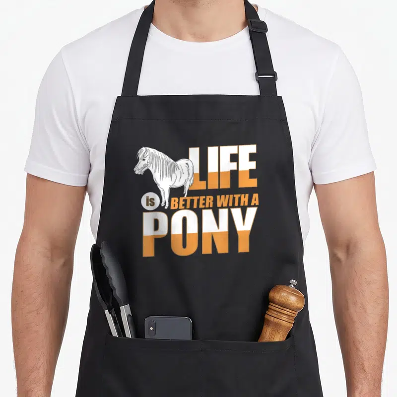 Tablier de cuisine noir avec illustration poney blanc et texte Life is Better with a Pony en orange et blanc.