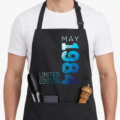 Tablier de cuisine noir avec inscription May 1984 Limited Edition en bleu dégradé et effet vieilli vertical.
