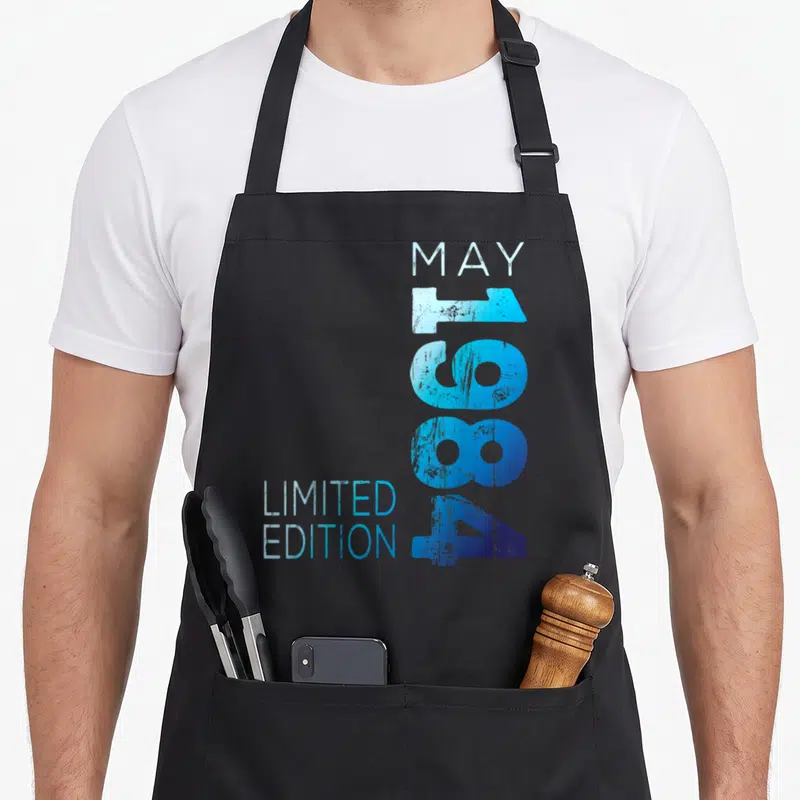 Tablier de cuisine noir avec inscription May 1984 Limited Edition en bleu dégradé et effet vieilli vertical.