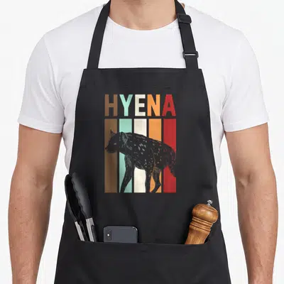 Tablier de cuisine noir avec illustration rétro d'une hyène et texte Hyena en lettres multicolores.