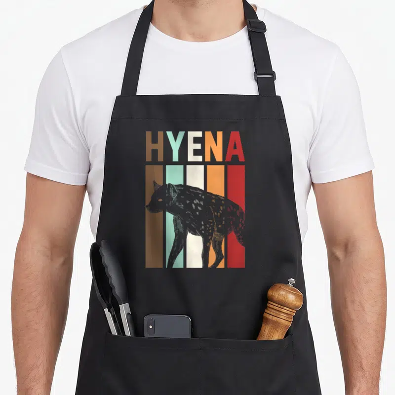 Tablier de cuisine noir avec illustration rétro d'une hyène et texte Hyena en lettres multicolores.