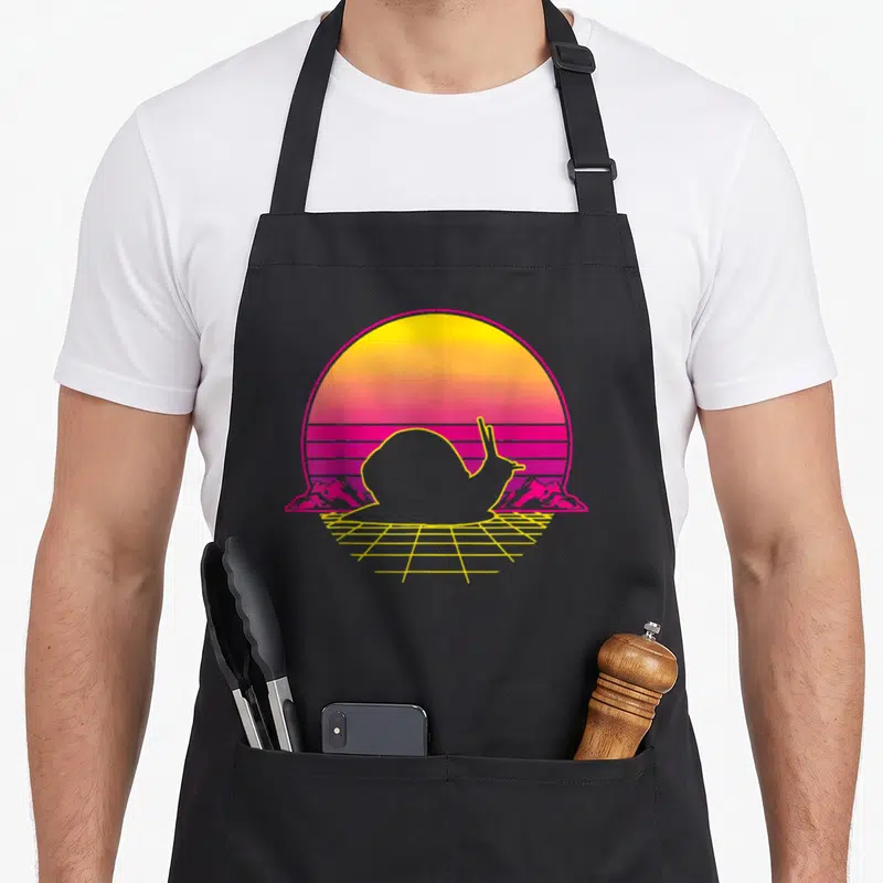 Tablier de cuisine noir avec illustration d'un escargot au contour jaune sur fond de soleil synthétique rose et orange.