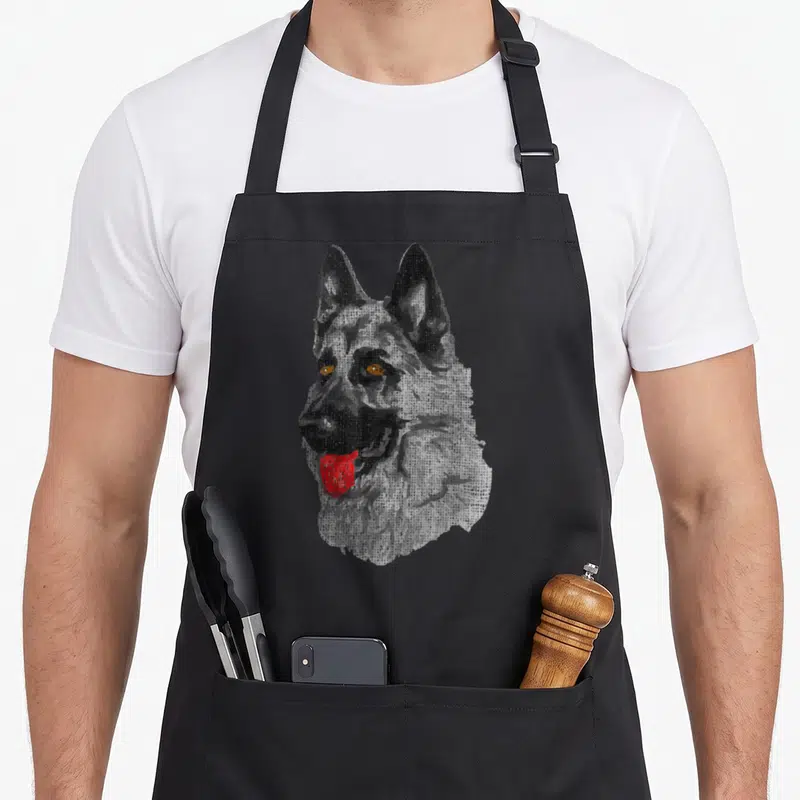 Tablier de cuisine noir avec illustration rétro d'un Berger Allement aux yeux dorés et langue rouge vif.