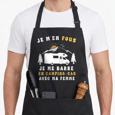 Tablier de cuisine noir avec illustration d'un camping-car blanc, montagnes et texte Je m'en fous je me barre en camping-car avec ma femme.