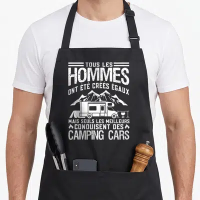 Tablier de cuisine noir avec inscription blanche sur les hommes et les camping cars au milieu d'un paysage montagneux.