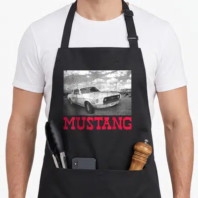 Tablier de cuisine noir avec illustration d'une Ford Mustang 1967 et le texte MUSTANG en rose vif.