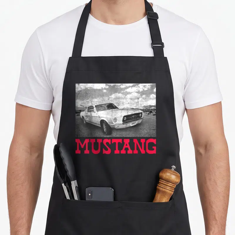 Tablier de cuisine noir avec illustration d'une Ford Mustang 1967 et le texte MUSTANG en rose vif.