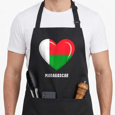 Tablier de cuisine noir avec un grand cœur affichant les couleurs du drapeau malgache et le texte MADAGASCAR en blanc.