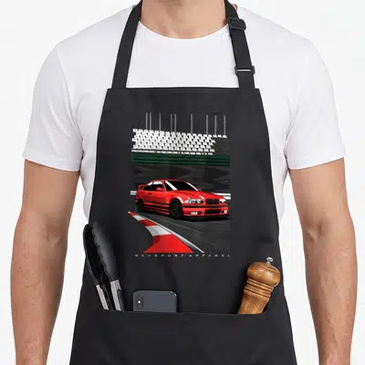Tablier de cuisine noir avec illustration d'une BMW E36 rouge effectuant un drift sur une piste de course.