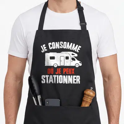 Tablier de cuisine noir avec illustration de camping-car et texte Je consomme où je peux stationner en blanc et rouge.
