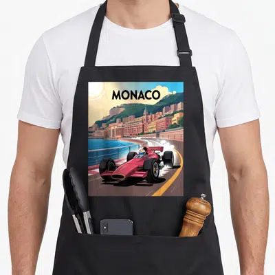Tablier de cuisine noir avec une illustration vintage d'une voiture de course rose à Monaco 1937 sur un circuit côtier.