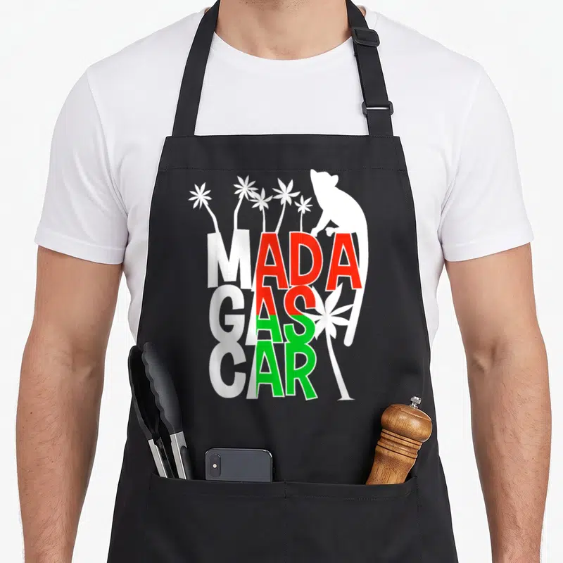 Tablier de cuisine noir avec texte Madagascar aux couleurs du drapeau et silhouettes de lémuriens blancs.