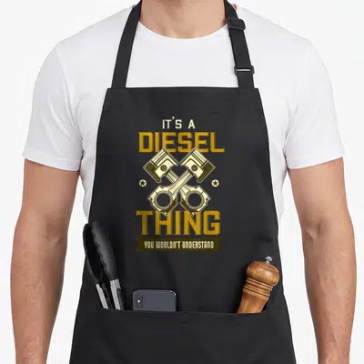 Tablier de cuisine noir avec deux pistons croisés et le texte It's a diesel thing vous n'auriez pas compris en jaune et marron.