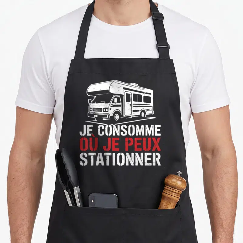 Tablier de cuisine noir avec illustration camping-car blanc et texte Je consomme où je peux stationner en rouge et blanc.