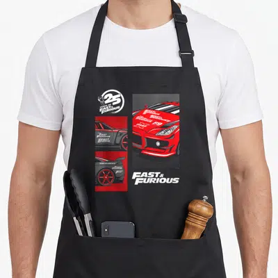 Tablier de cuisine noir avec illustration d'une voiture rouge, logos de films et texte 25 ans Fast & Furious en blanc et gris.
