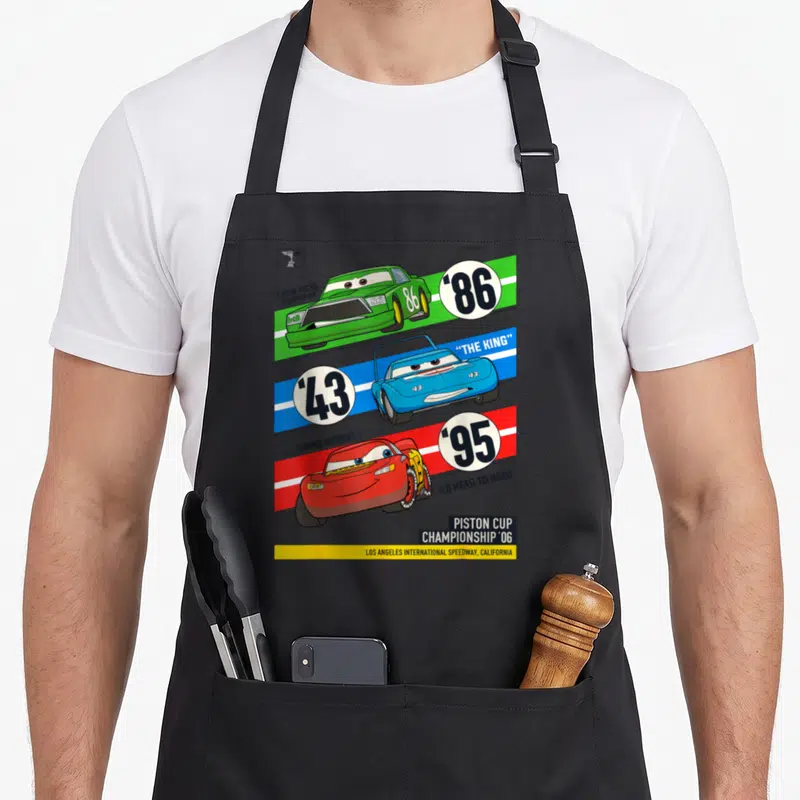 Tablier de cuisine noir avec trois voitures de course colorées et les numéros 86, 43 et 95 imprimés en grand.