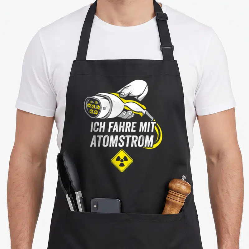 Tablier de cuisine noir avec une illustration de prise de recharge et le texte Ich fahre mit Atomstrom en blanc et jaune.