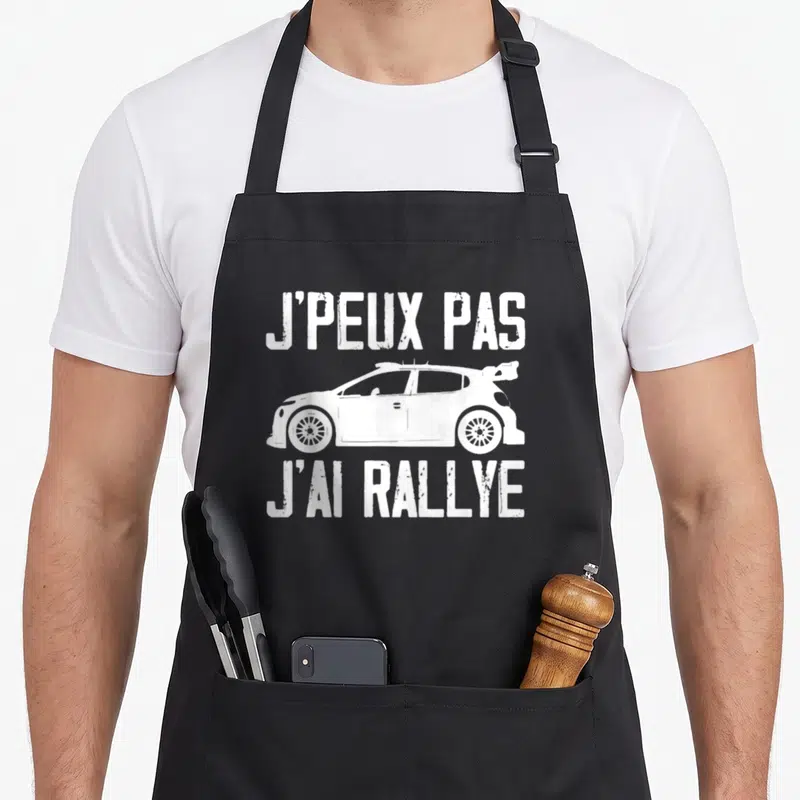 Tablier de cuisine noir avec inscription blanche J'peux pas j'ai rallye et silhouette de voiture de sport.