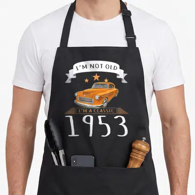 Tablier de cuisine noir avec une illustration de voiture orange vintage et le texte I'm Not Old I'm A Classic 1953
