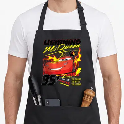 Tablier de cuisine noir avec Lightning McQueen rouge, flammes jaunes et numéro 95 imprimé au centre.