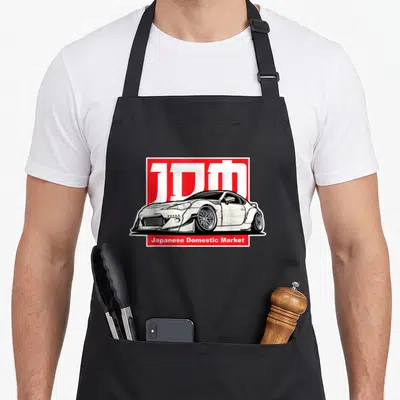 Tablier de cuisine noir avec illustration d'une voiture blanche et le logo JDM rouge.