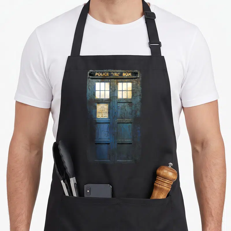 Tablier de cuisine noir avec une illustration détaillée d'une cabine téléphonique bleue usée et des inscriptions blanches sur fond sombre.