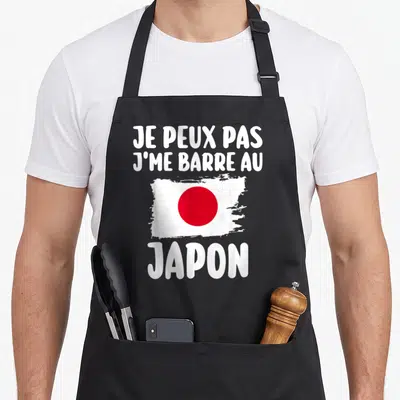 Tablier de cuisine noir avec l'inscription Je peux pas j me barre au Japon et un drapeau japonais stylisé.