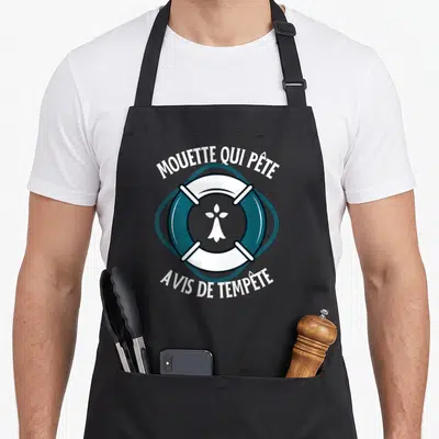Tablier de cuisine noir avec une illustration de bouée et le texte Mouette qui pète Avis de tempête.