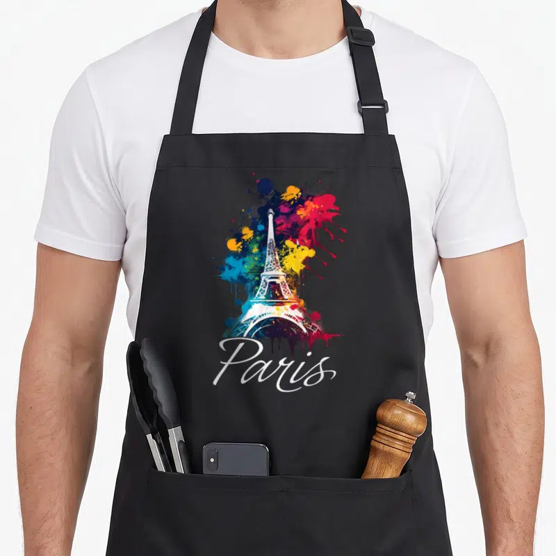 Tablier de cuisine noir avec une illustration colorée de la Tour Eiffel et le mot Paris en écriture cursive blanche.