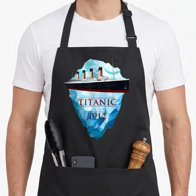 Tablier de cuisine noir avec illustration d'un paquebot reposant sur un iceberg bleu portant les mots Titanic et 1912 en lettres rouges.