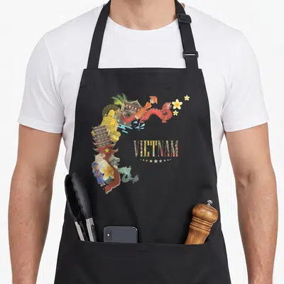 Tablier de cuisine noir avec carte du Vietnam ornée de symboles culturels et du mot Vietnam en lettres texturées.