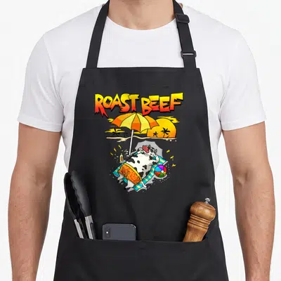 Tablier de cuisine noir avec une vache bronzant sous un parasol et le texte Roast Beef au-dessus.
