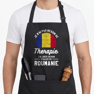 Tablier de cuisine noir avec un drapeau roumain circulaire et le texte J'ai juste besoin d'aller en Roumanie imprimé en blanc.