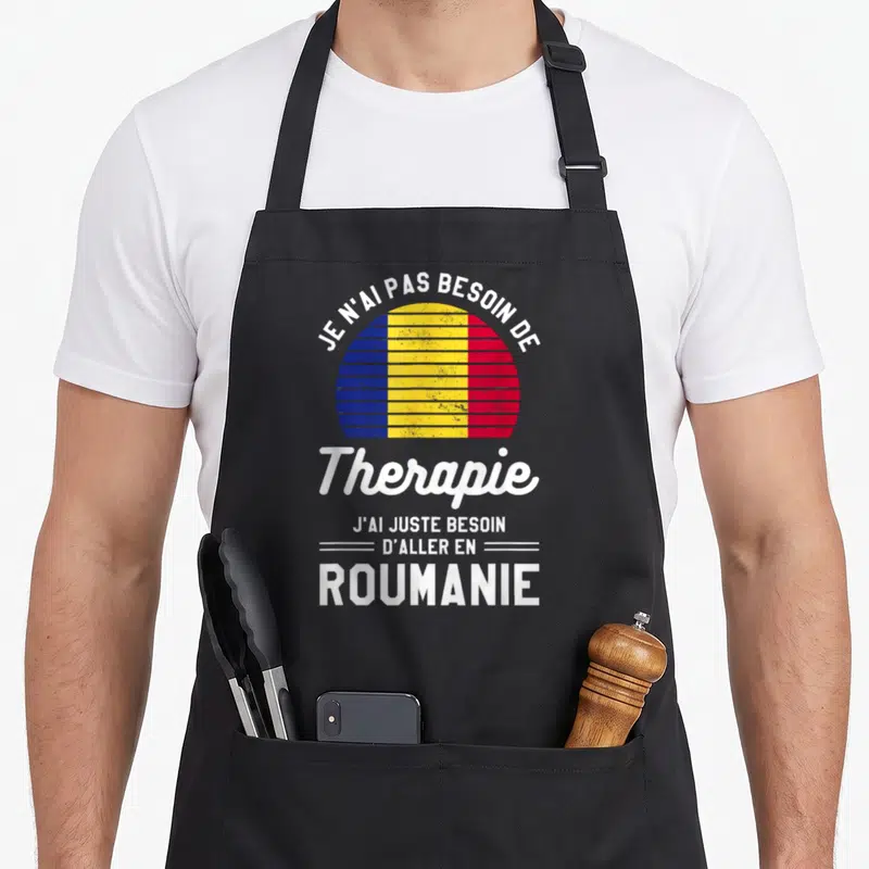 Tablier de cuisine noir avec un drapeau roumain circulaire et le texte J'ai juste besoin d'aller en Roumanie imprimé en blanc.