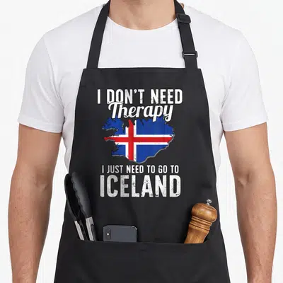 Tablier de cuisine noir avec une carte de l'Islande et un texte humoristique sur les voyages.