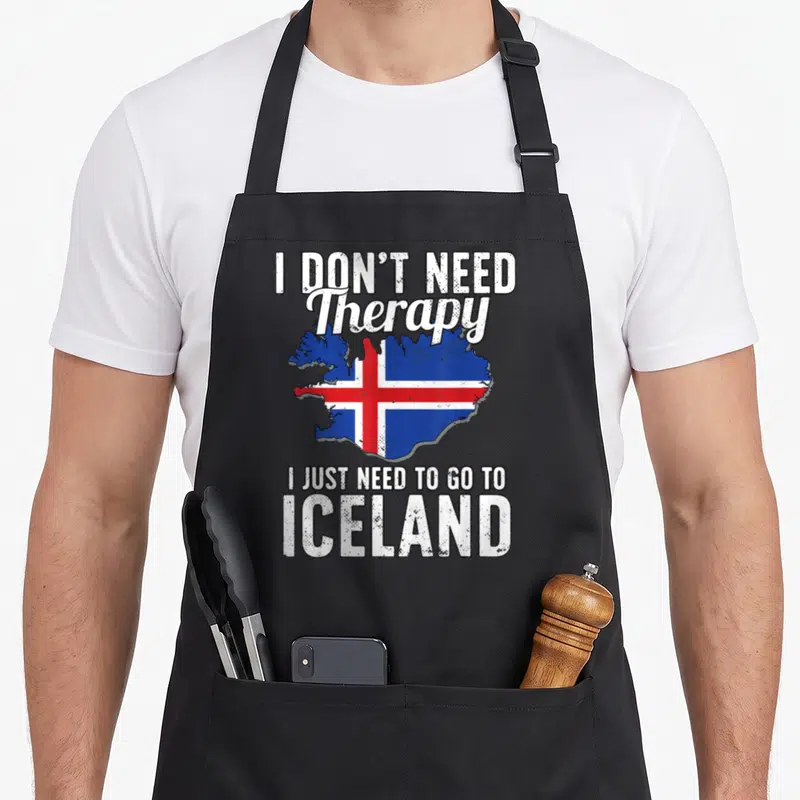 Tablier de cuisine noir avec une carte de l'Islande et un texte humoristique sur les voyages.