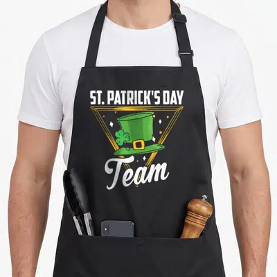 Tablier de cuisine noir avec chapeau vert St. Patrick's Day Team et cadre géométrique doré.
