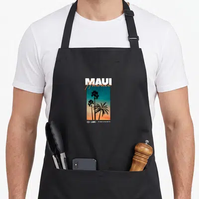 Tablier de cuisine noir avec illustration de palmiers au coucher du soleil et texte MAUI Hawaii en typographie blanche et orange.