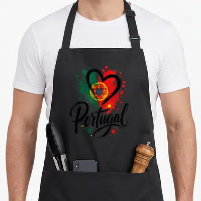 Tablier de cuisine noir avec un cœur contenant le drapeau portugais et l'écriture Portugal sur fond de taches de peinture.