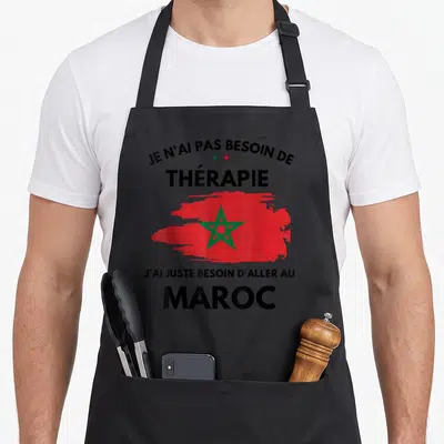 Tablier de cuisine noir avec inscription humoristique sur le voyage au Maroc et le drapeau national rouge et vert.